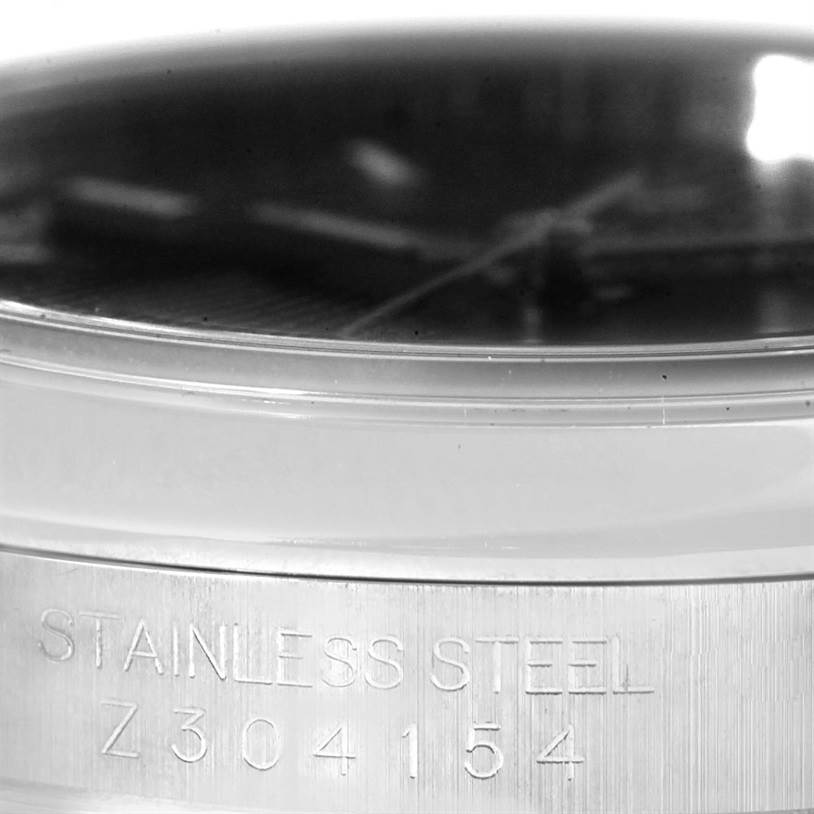 The image shows a close-up side view of a Rolex Datejust 116200 Men
s Stainless Steel Black Dial 116200 Men
s Stainless Steel Black Dial watch, highlighting the stainless steel case and the engraved serial number.