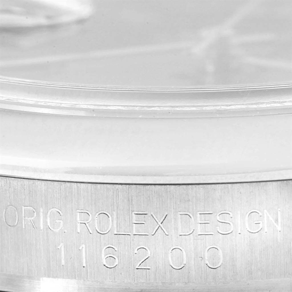 The image shows a close-up angle of the side of the Rolex Datejust 116200 Men
s Stainless Steel Black Dial 116200 Men
s Stainless Steel Black Dial watch, highlighting its serial number and "ORIG. ROLEX DESIGN."