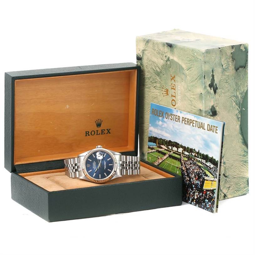 The image shows a Rolex Datejust 16234 Men's Stainless Steel Blue Dial 16234 Men's Stainless Steel Blue Dial watch in an open box with its packaging and booklet displayed behind it.