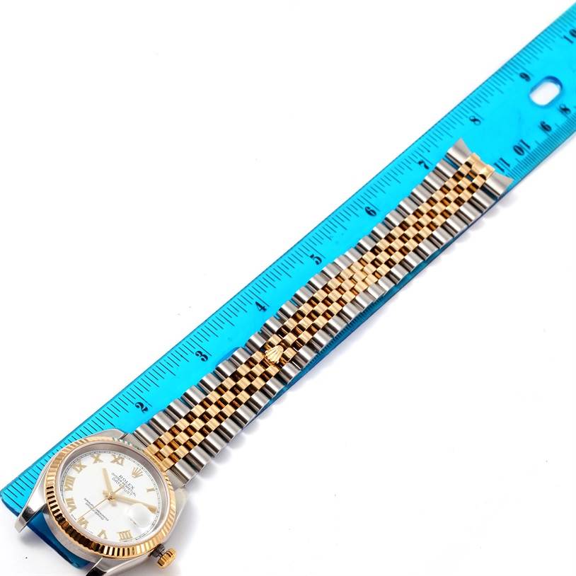 The image shows a Rolex Datejust 116233 Men's Stainless Steel White Dial 116233 Men's Stainless Steel White Dial watch with a gold and silver jubilee bracelet, next to a blue ruler for scale.