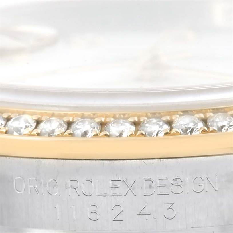 The image shows a close-up of a Rolex Datejust 116243 Stainless Steel White Dial 116243 Stainless Steel White Dial watch
s diamond-studded bezel and part of the case with engraved text.