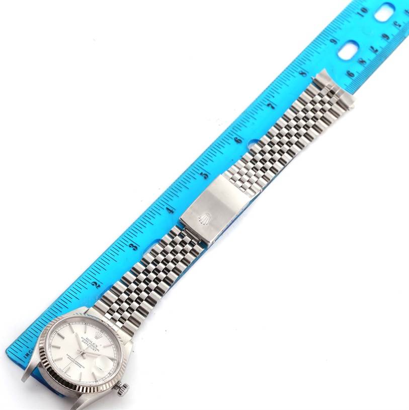 The image shows a Rolex Datejust 16234 Men
s Stainless Steel Silver Dial 16234 Men
s Stainless Steel Silver Dial watch laid flat with a silver Jubilee bracelet next to a blue ruler.