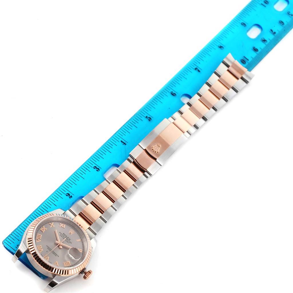 This image shows the Rolex Datejust 116201 Men
s Steel and Gold (two tone) Grey Dial 116201 Men
s Steel and Gold (two tone) Grey Dial watch laying flat with a blue ruler measuring its length.