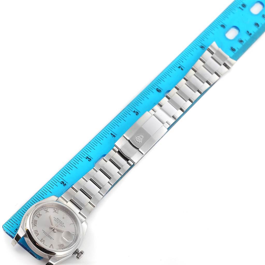 This image shows the Rolex Datejust 116200 Men
s Stainless Steel Silver Dial 116200 Men
s Stainless Steel Silver Dial watch laid flat with its face and bracelet alongside a blue ruler for size reference.