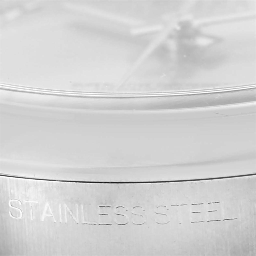 This close-up image of the Rolex Datejust 116200 Men
s Stainless Steel Silver Dial 116200 Men
s Stainless Steel Silver Dial watch shows the stainless steel inscription on its side and part of the watch face and crystal.