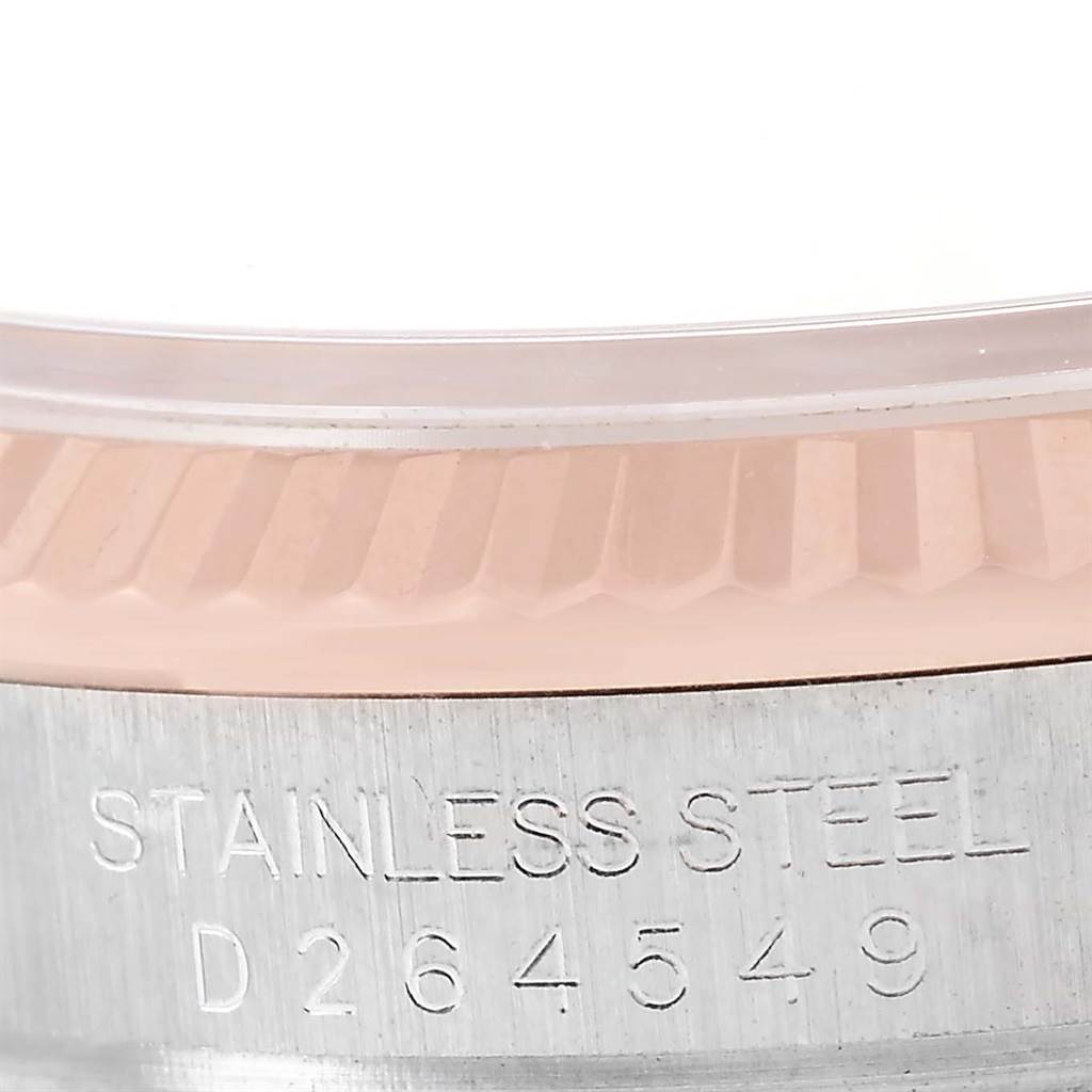 This close-up image of the Rolex Datejust 116231 Men's Steel and Gold (two tone) Black Dial 116231 Men's Steel and Gold (two tone) Black Dial watch shows part of the fluted bezel and engraved serial number on the stainless steel case.