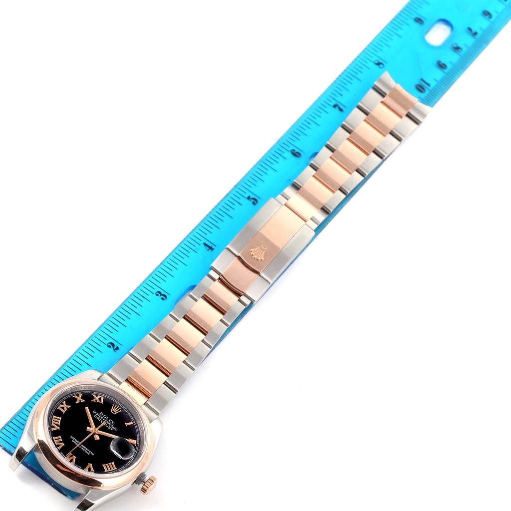 The image shows a Rolex Datejust 116201 Steel and Gold (two tone) Black Dial 116201 Steel and Gold (two tone) Black Dial watch laid flat next to a ruler, displaying both its face and two-tone bracelet.