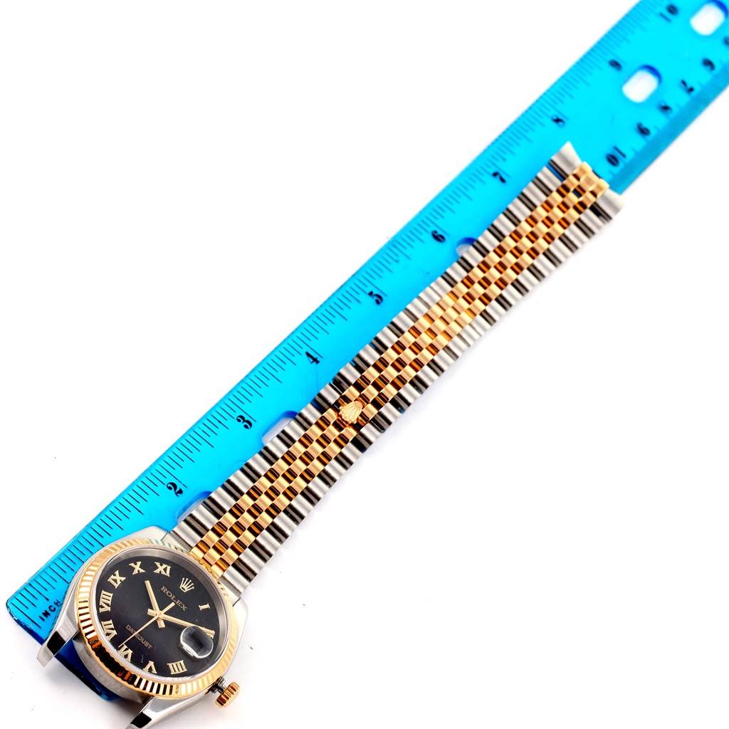 The image shows the Rolex Datejust 116233 Men's Stainless Steel Black Dial 116233 Men's Stainless Steel Black Dial watch at a top-down angle, highlighting the watch face, bezel, and two-tone bracelet next to a ruler.