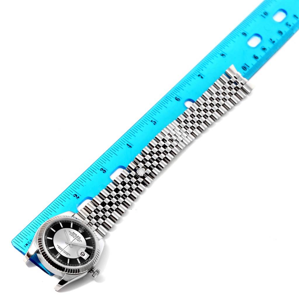 The Rolex Datejust 116234 Men's Stainless Steel Black Dial 116234 Men's Stainless Steel Black Dial watch is shown from an angled top view, with the face, bezel, and stainless steel bracelet displayed alongside a ruler.