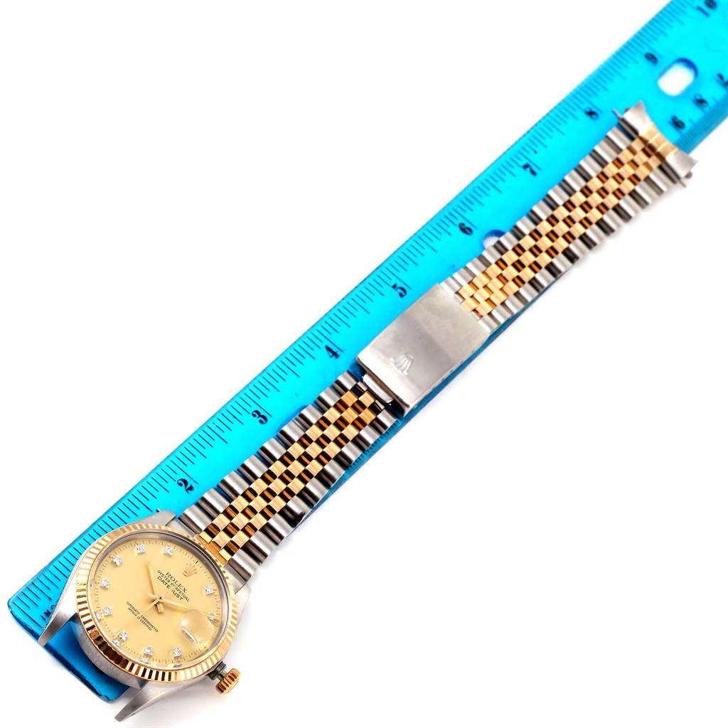 The image shows the full strap and face of a Rolex Datejust 16013 Men
s Stainless Steel Champagne Dial 16013 Men
s Stainless Steel Champagne Dial watch alongside a blue ruler.