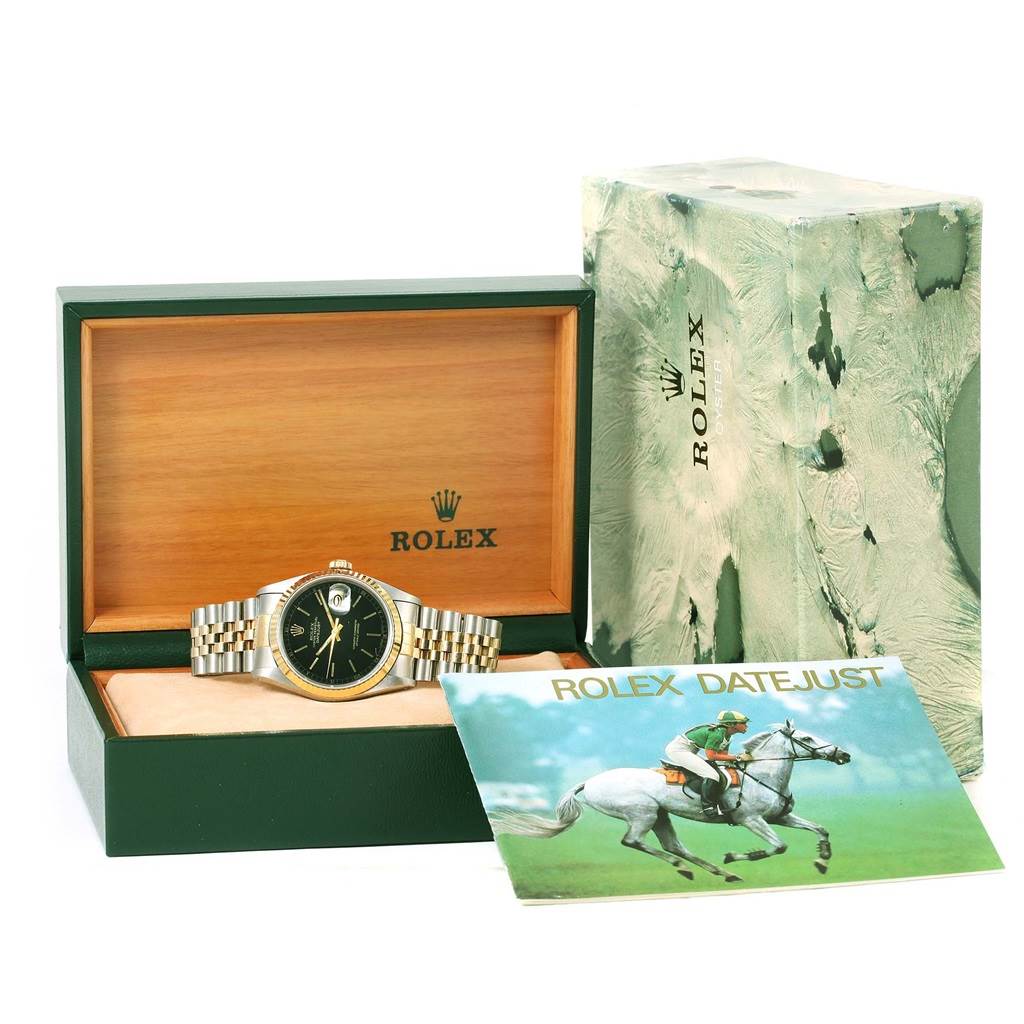 The image shows a Rolex Datejust 16233 Men's Steel and Gold (two tone) Black Dial 16233 Men's Steel and Gold (two tone) Black Dial watch with its bracelet and face visible, placed in an open green and wooden box alongside its outer packaging and booklet.