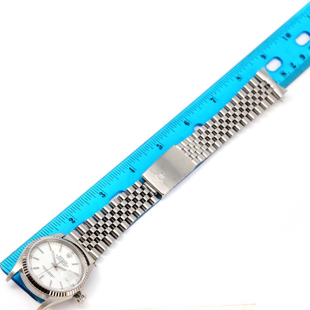 This image shows a Rolex Datejust 16234 Men
s Stainless Steel White Dial 16234 Men
s Stainless Steel White Dial watch laid flat with a blue ruler to measure its band length.