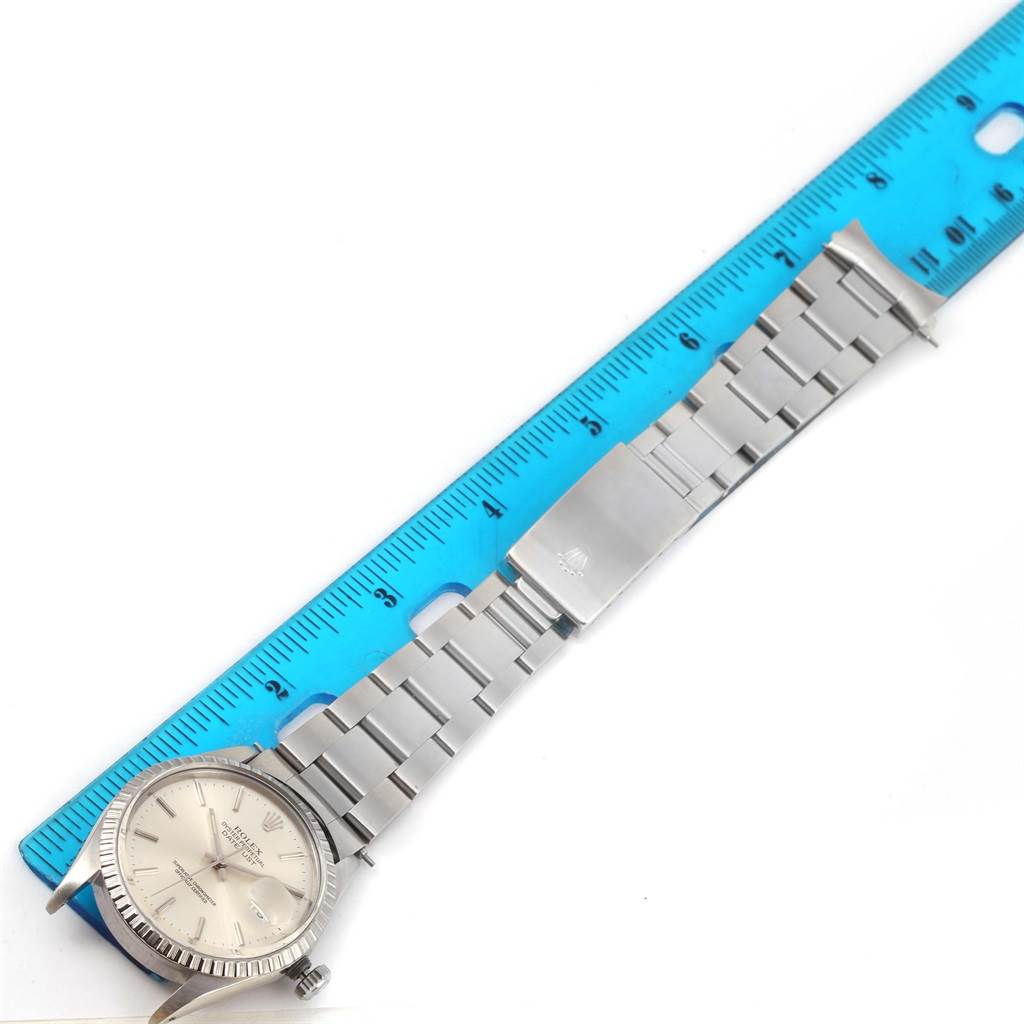 The Rolex Datejust 16030 Men's Stainless Steel Silver Dial 16030 Men's Stainless Steel Silver Dial watch is shown from a top-down angle, displaying the full watch with its steel bracelet and part of a blue ruler.