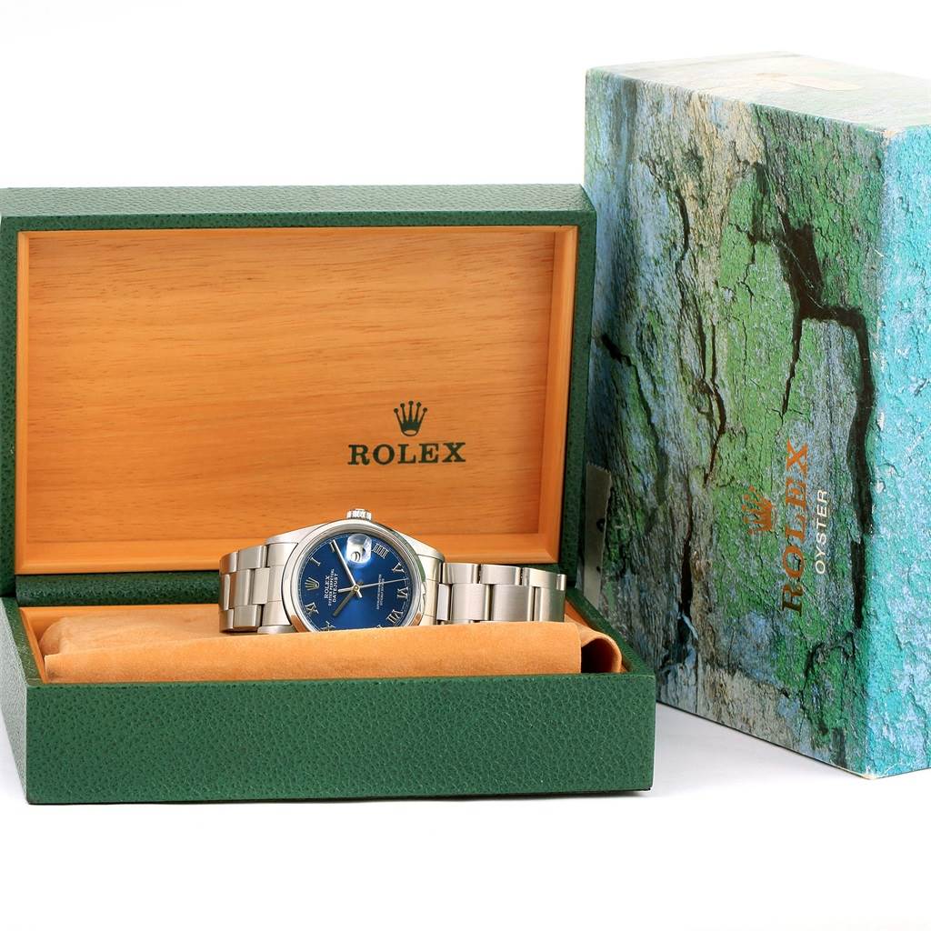 The Rolex Datejust 16200 Men's Stainless Steel Blue Dial 16200 Men's Stainless Steel Blue Dial watch is shown front-facing in its open green and wooden box, with its outer box beside it.