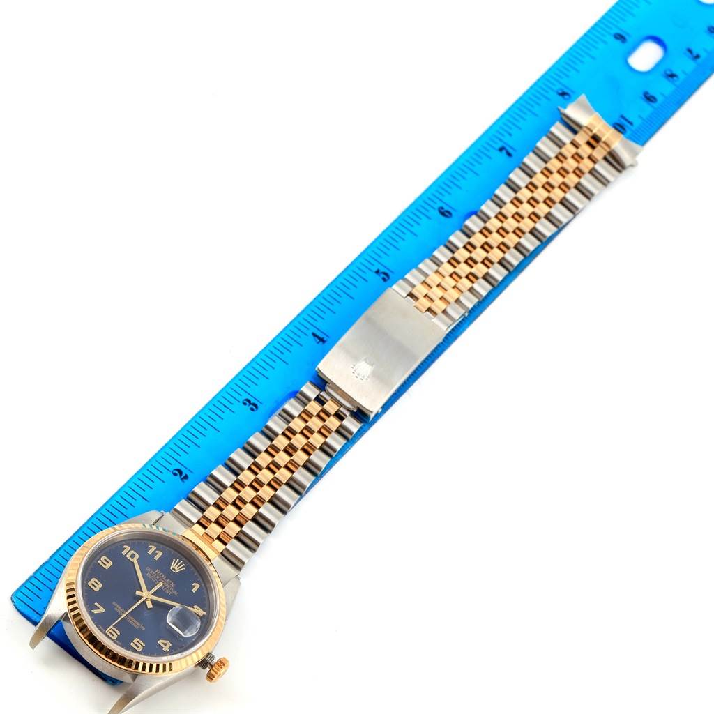 The image shows a Rolex Datejust 16233 Men's Steel and Gold (two tone) Blue Dial 16233 Men's Steel and Gold (two tone) Blue Dial watch laid flat with a ruler for measurement, displaying the face, bracelet, and clasp.