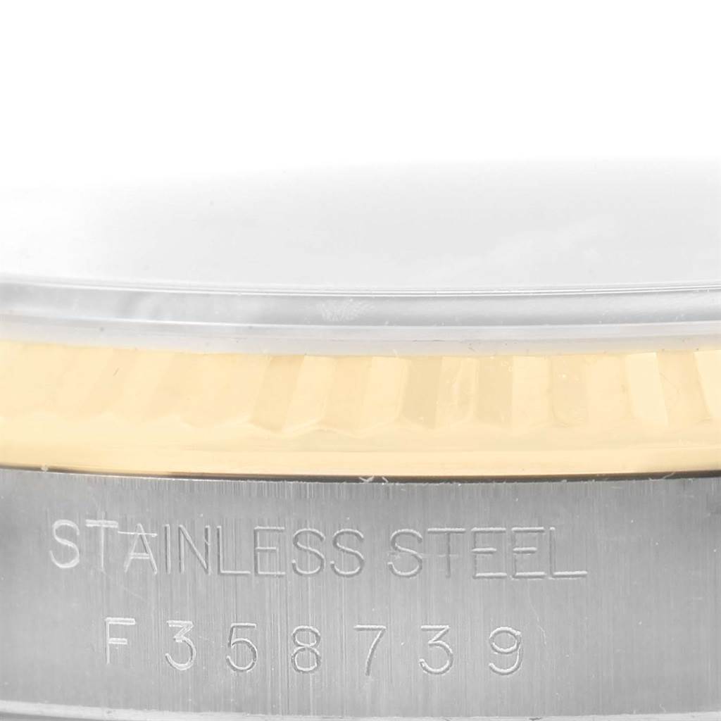 This close-up shot of the Rolex Datejust 16233 Men's Steel and Gold (two tone) Blue Dial 16233 Men's Steel and Gold (two tone) Blue Dial watch shows the engraved stainless steel case and part of the fluted bezel.