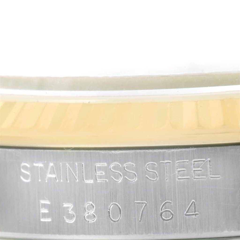 This close-up image of a Rolex Datejust 16233 Men's Steel and Gold (two tone) Champagne Dial 16233 Men's Steel and Gold (two tone) Champagne Dial shows the engraved serial number and part of the stainless steel casing and fluted bezel.