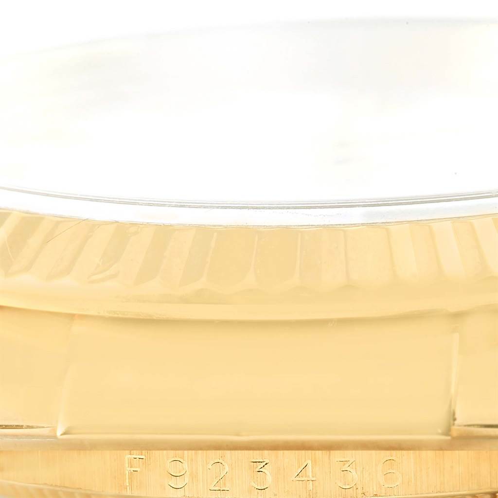 The image shows the fluted bezel and case of a Rolex Datejust 116138 Men's Yellow Gold White Dial 116138 Men's Yellow Gold White Dial watch, focusing on the serial number engraved at the bottom.