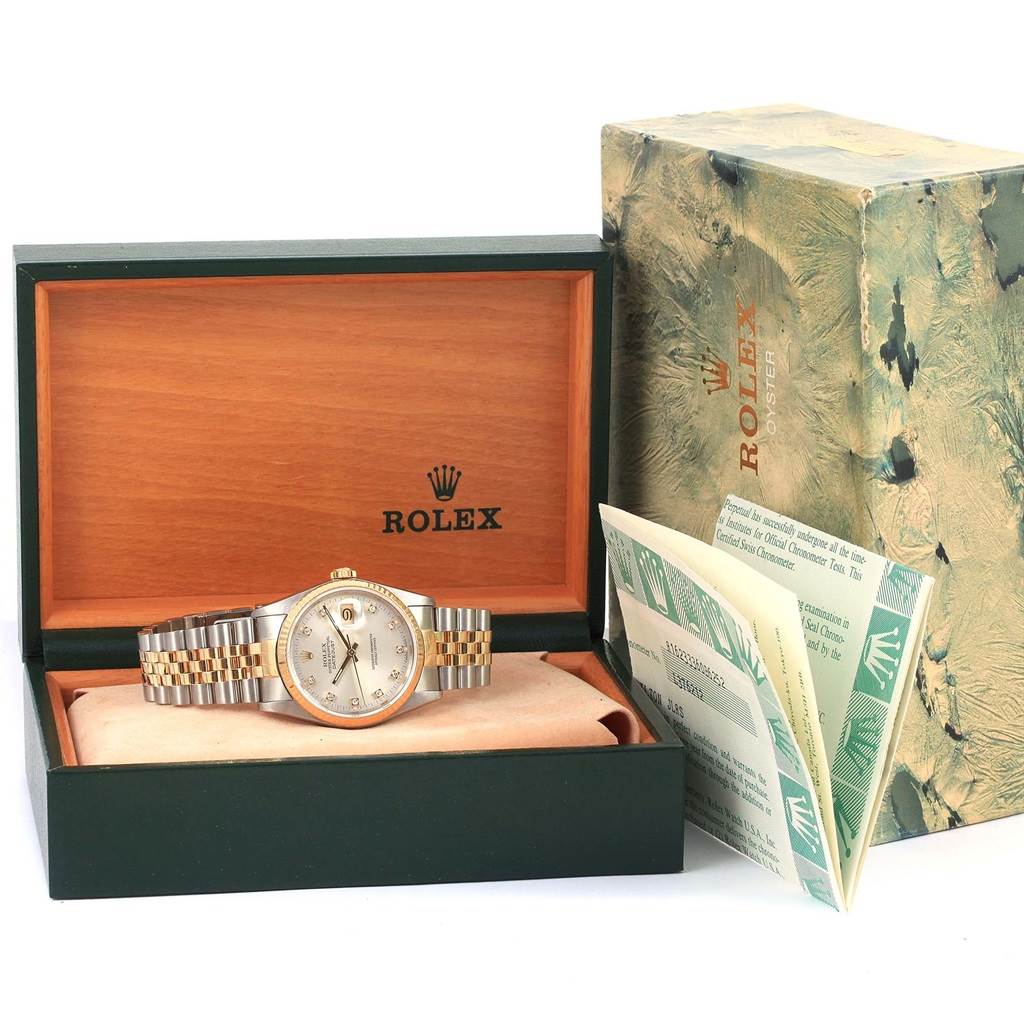 The image shows a Rolex Datejust 16233 Men
s Steel and Gold (two tone) Silver Dial 16233 Men
s Steel and Gold (two tone) Silver Dial watch inside its open box, with its original packaging and papers beside it.