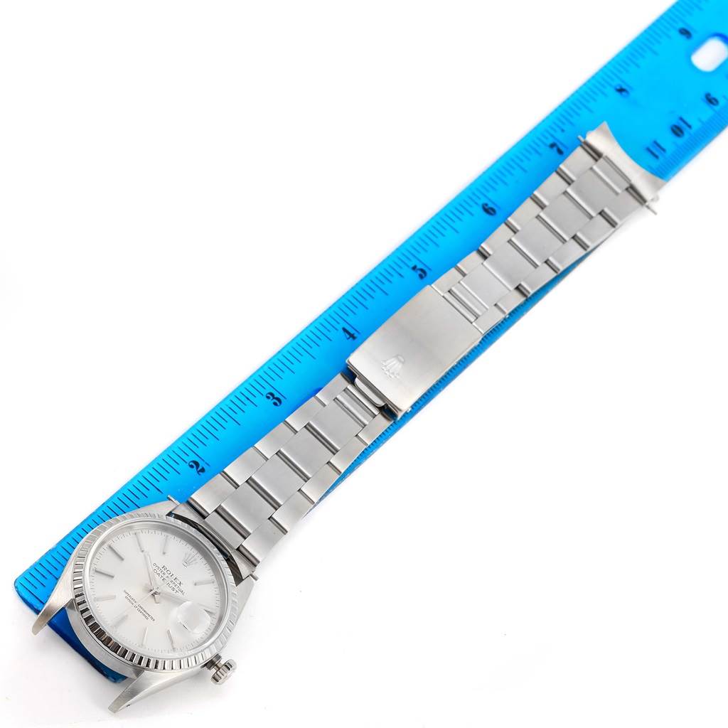 The Rolex Datejust 16220 Men
s Stainless Steel Silver Dial 16220 Men
s Stainless Steel Silver Dial watch is shown from an overhead angle, including the dial, bracelet, and clasp aligned with a blue ruler.