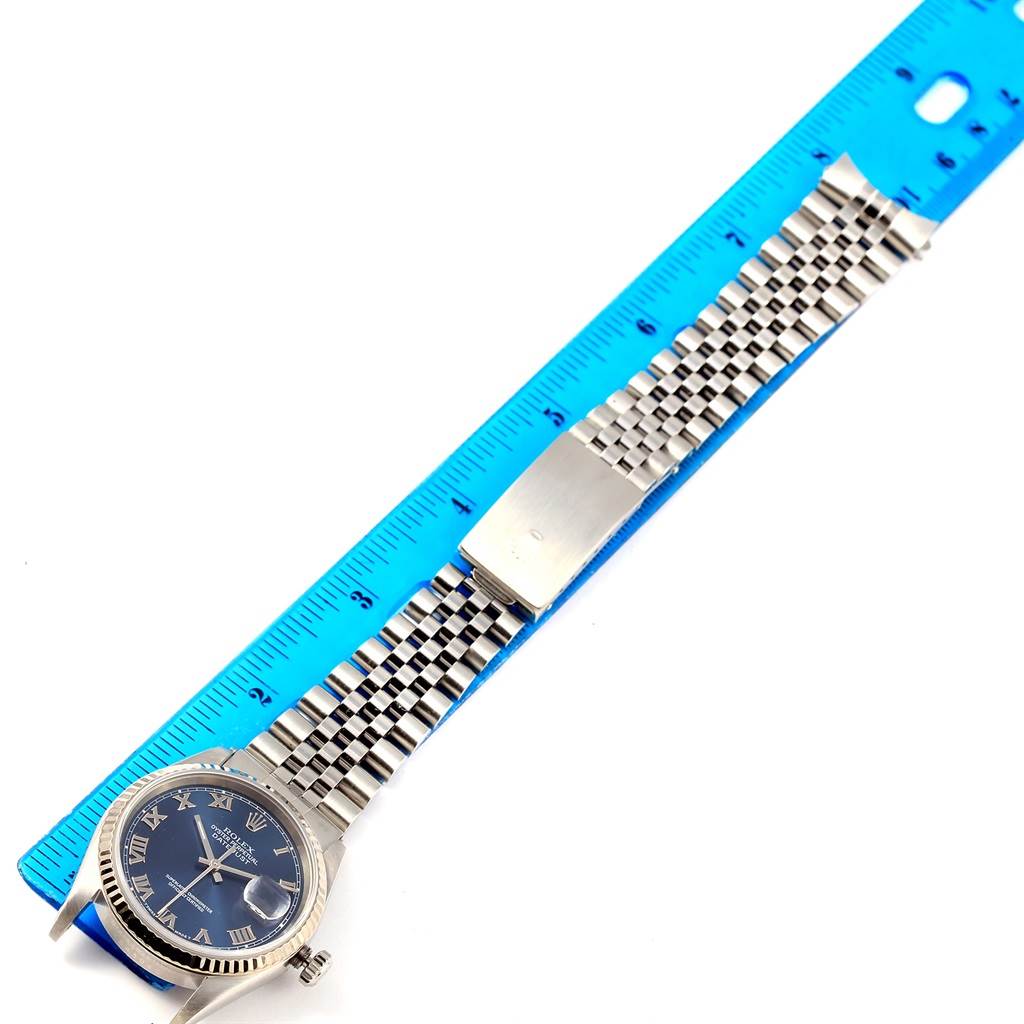 The image shows a top-down view of a Rolex Datejust 16234 Men's Stainless Steel Blue Dial 16234 Men's Stainless Steel Blue Dial watch with a blue dial and silver bracelet alongside a ruler.