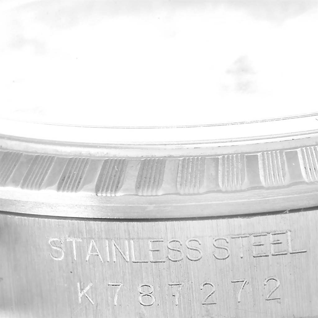 The image shows a close-up of the fluted bezel and case engraving of a Rolex Datejust 16220 Men
s Stainless Steel Silver Dial 16220 Men
s Stainless Steel Silver Dial watch, highlighting the stainless steel material and serial number.