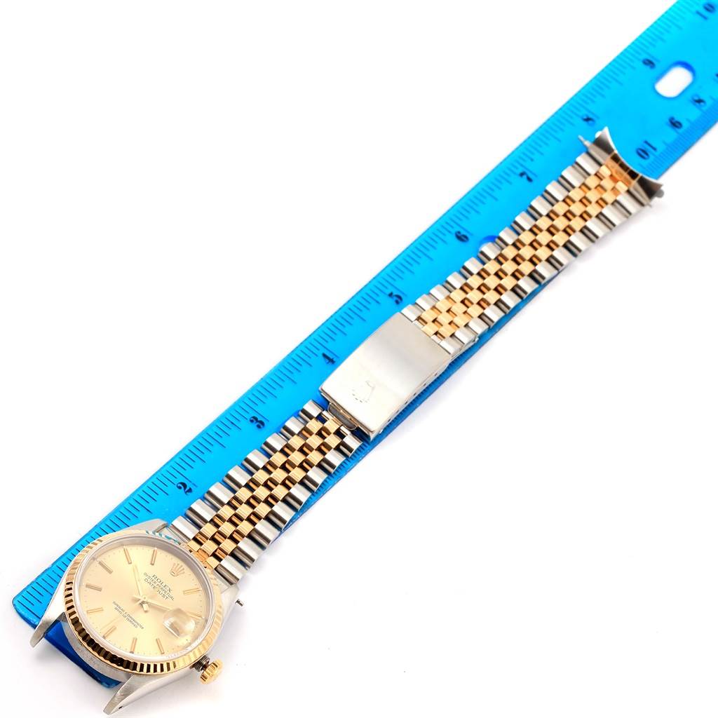 The Rolex Datejust 16233 Men's Steel and Gold (two tone) Champagne Dial 16233 Men's Steel and Gold (two tone) Champagne Dial watch is shown flat with its jubilee bracelet extended and measured against a blue ruler.