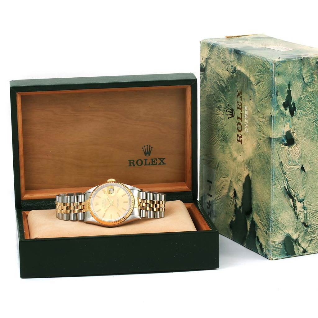 The Rolex Datejust 16233 Men's Steel and Gold (two tone) Champagne Dial 16233 Men's Steel and Gold (two tone) Champagne Dial watch is displayed front-facing in its open box, with visible packaging beside it.