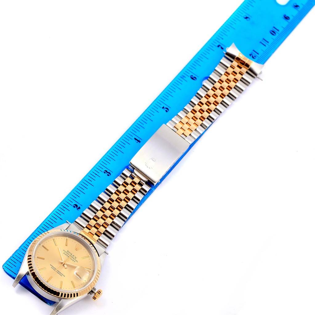 The image shows a Rolex Datejust 16233 Men's Steel and Gold (two tone) Champagne Dial 16233 Men's Steel and Gold (two tone) Champagne Dial watch laid flat, next to a blue ruler, displaying its face, bezel, crown, and bracelet.