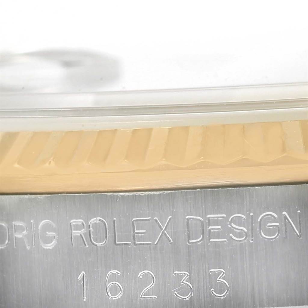 This close-up image shows the fluted bezel, crystal, and engravings on the side of the Rolex Datejust 16233 Men's Steel and Gold (two tone) Champagne Dial 16233 Men's Steel and Gold (two tone) Champagne Dial watch model 16233.