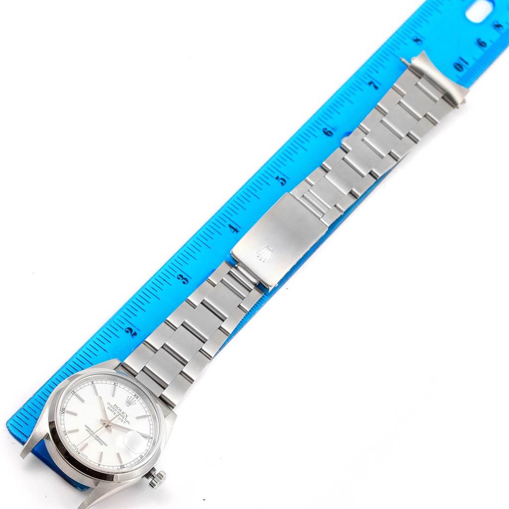 The image shows a Rolex Datejust 16200 Men
s Stainless Steel White Dial 16200 Men
s Stainless Steel White Dial watch lying flat with its silver bracelet fully extended next to a blue ruler.