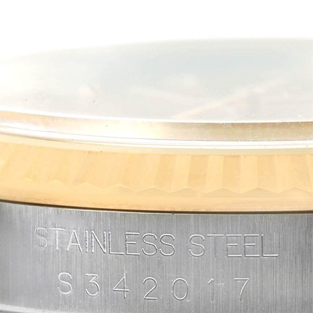 This close-up image of the Rolex Datejust 16233 Men's Steel and Gold (two tone) Champagne Dial 16233 Men's Steel and Gold (two tone) Champagne Dial shows the edge of the sapphire crystal and part of the stainless steel case with engravings.