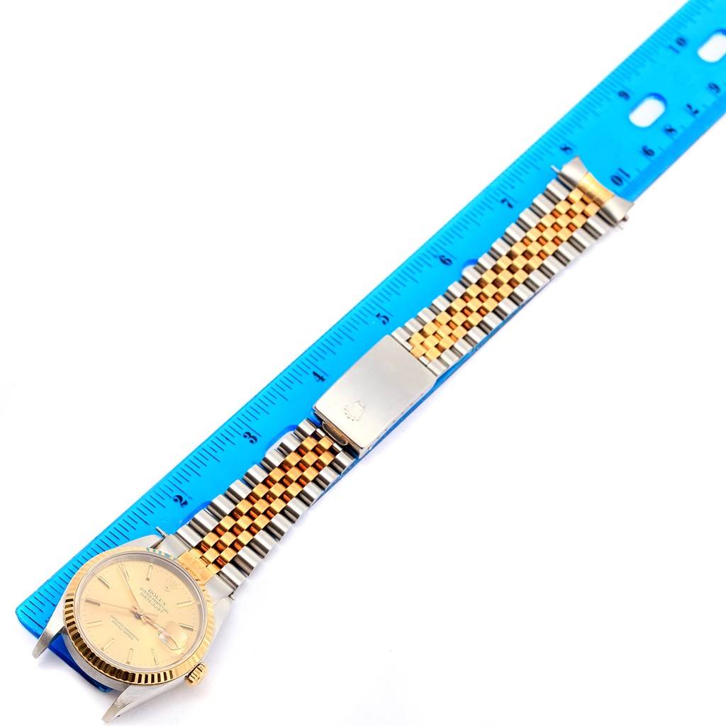 The Rolex Datejust 16233 Men's Steel and Gold (two tone) Champagne Dial 16233 Men's Steel and Gold (two tone) Champagne Dial watch is shown flat, displaying the full dial, bracelet, and clasp next to a ruler for scale.