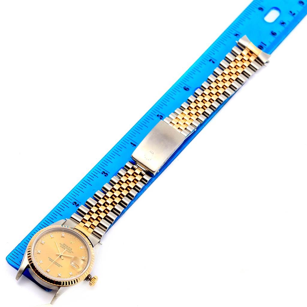 The Rolex Datejust 16233 Men's Steel and Gold (two tone) Champagne Dial 16233 Men's Steel and Gold (two tone) Champagne Dial watch is shown from a top-down angle, displaying the dial, bezel, crown, and Jubilee bracelet alongside a ruler.