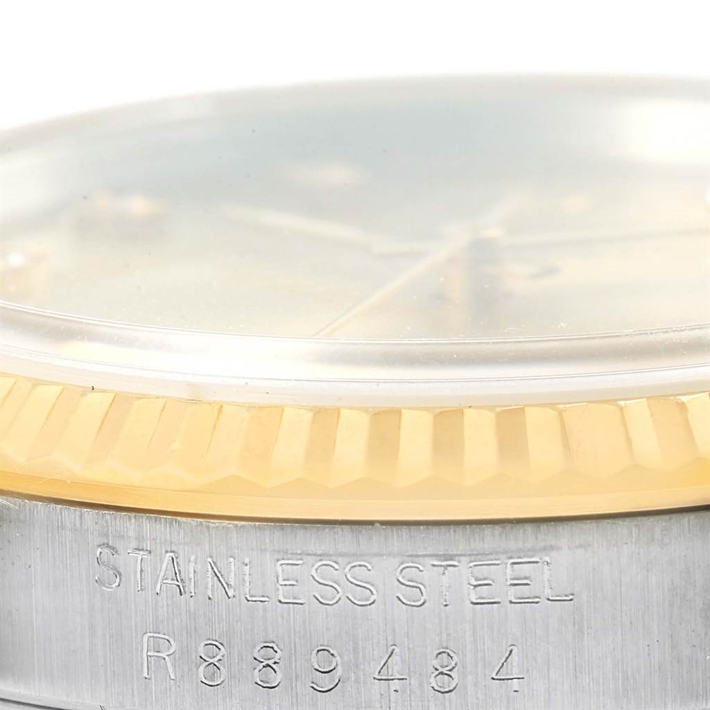 The image shows a close-up of the Rolex Datejust 16233 Men's Steel and Gold (two tone) Champagne Dial 16233 Men's Steel and Gold (two tone) Champagne Dial's bezel, partially covered crystal, and engraved stainless steel casing.
