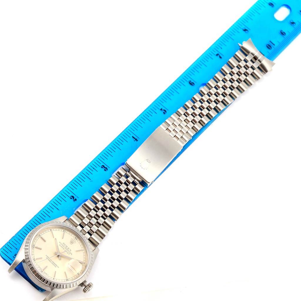 The Rolex Datejust 16220 Men's Stainless Steel Silver Dial 16220 Men's Stainless Steel Silver Dial watch is shown face-up with its full length and clasp visible, alongside a blue ruler for measurement.