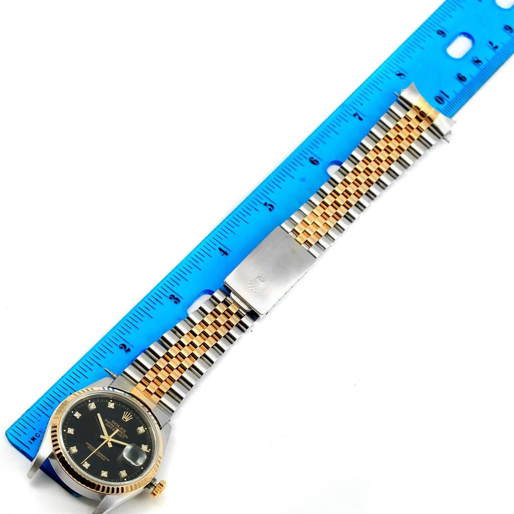 This top-down view shows a Rolex Datejust 16233 Steel and Gold (two tone) Black Dial 16233 Steel and Gold (two tone) Black Dial watch with its dial face, bracelet, and clasp alongside a measuring ruler.