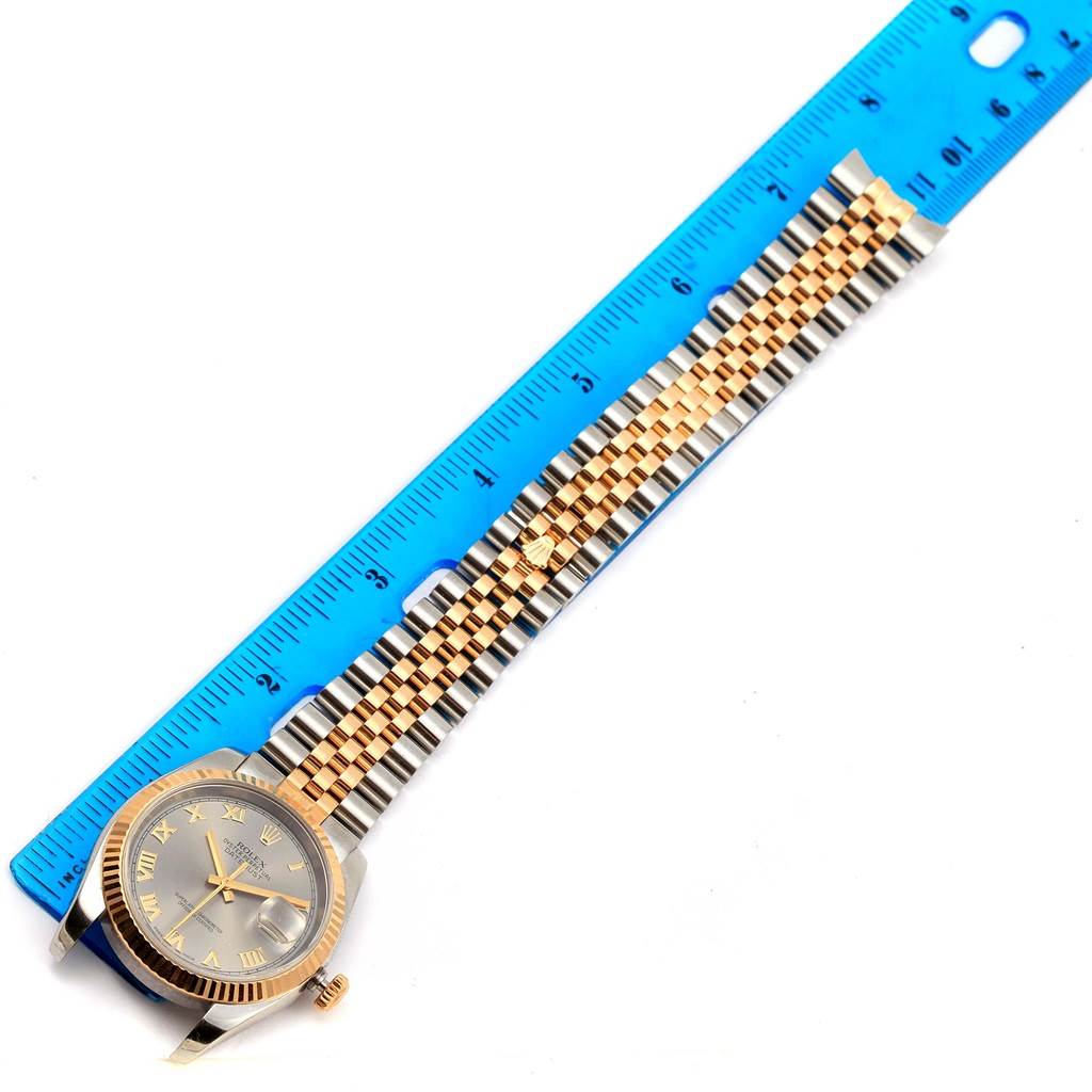 The Rolex Datejust 116233 Men's Stainless Steel Grey Dial 116233 Men's Stainless Steel Grey Dial watch is shown from an overhead angle, displaying the face and its two-tone metal bracelet against a ruler.