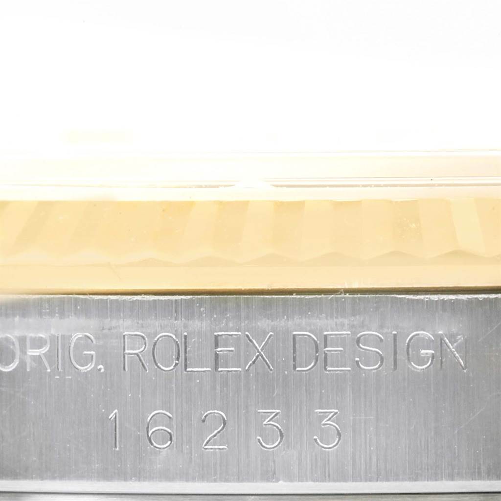 This image shows a close-up of the Rolex Datejust 16233 Men's Steel and Gold (two tone) White Dial 16233 Men's Steel and Gold (two tone) White Dial model's fluted bezel and part of the metal watch case with a serial number.