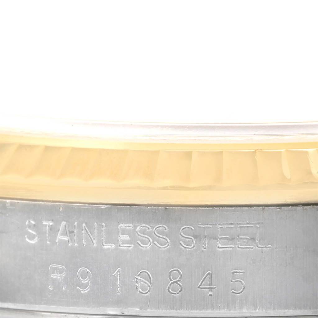 This close-up image of the Rolex Datejust 16233 Men's Steel and Gold (two tone) White Dial 16233 Men's Steel and Gold (two tone) White Dial watch shows the engraved "Stainless Steel" text and part of the fluted bezel.