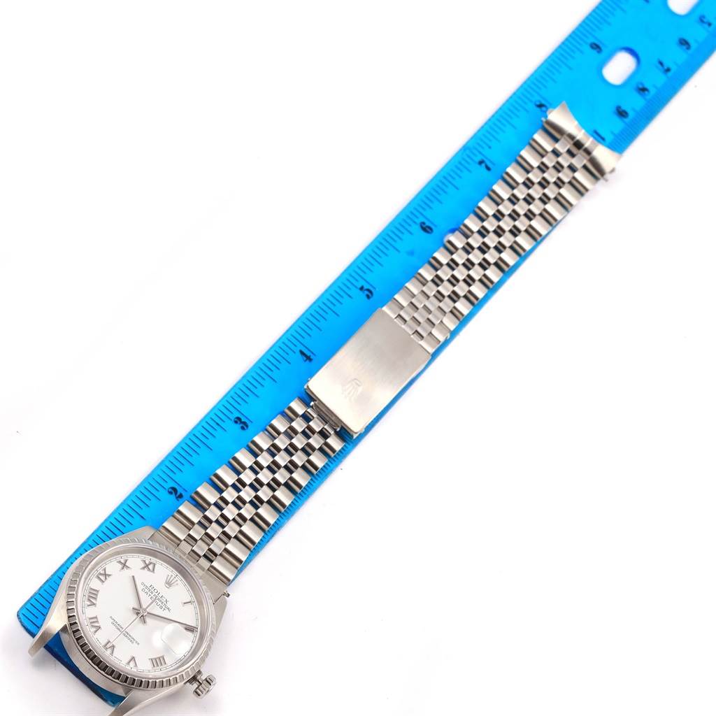 This image shows a Rolex Datejust 16220 Men's Stainless Steel White Dial 16220 Men's Stainless Steel White Dial watch laid flat next to a ruler, featuring its face, bracelet, and clasp.