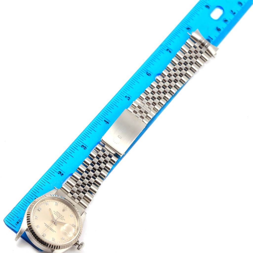 The image shows a Rolex Datejust 16234 Men's Stainless Steel Silver Dial 16234 Men's Stainless Steel Silver Dial watch displayed next to a blue ruler, highlighting the dial, bracelet, and clasp from a top-down angle.