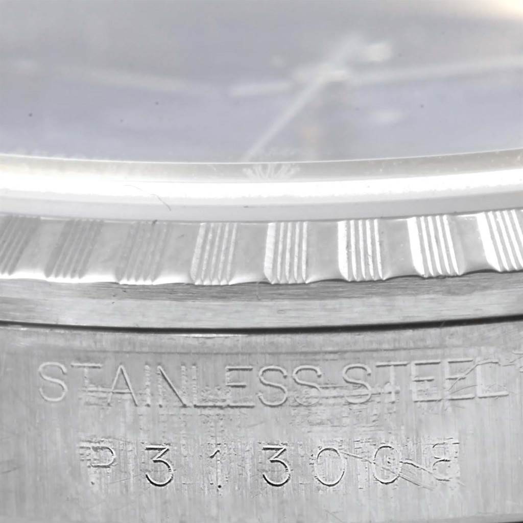 The image shows a close-up of the bezel and part of the case of a Rolex Datejust 16220 Men's Stainless Steel Blue Dial 16220 Men's Stainless Steel Blue Dial watch, highlighting the fluted bezel and the serial number engraving.