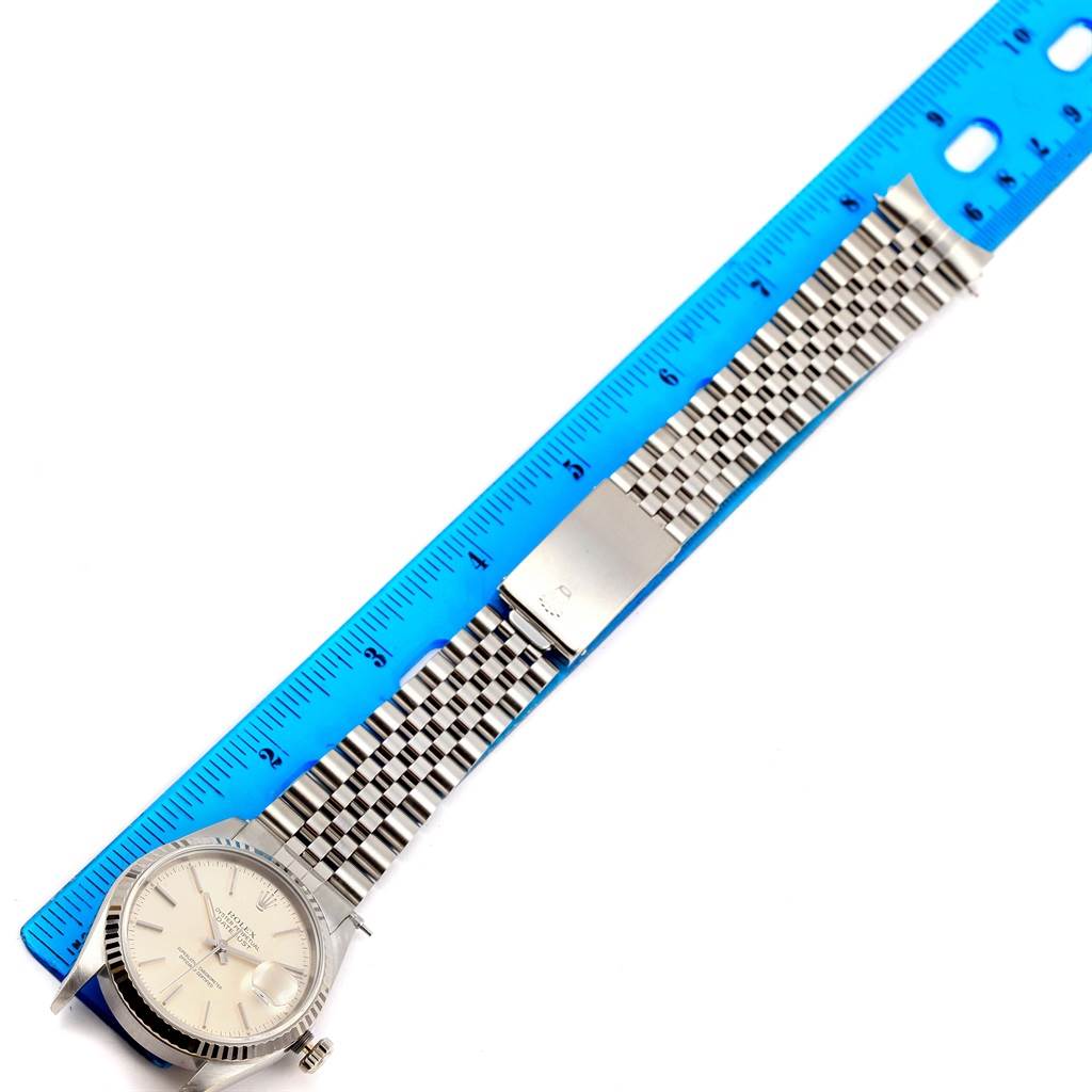 The Rolex Datejust 16234 Men's Stainless Steel Silver Dial 16234 Men's Stainless Steel Silver Dial watch is shown from an overhead angle, displaying the face, bracelet, and clasp alongside a blue ruler for scale.