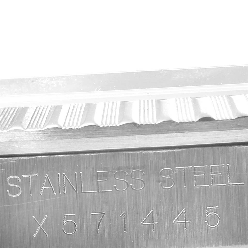 The image shows a close-up angle of the Rolex Datejust 16220 Men
s Stainless Steel Silver Dial 16220 Men
s Stainless Steel Silver Dial wristwatch bezel and part of the case with "STAINLESS STEEL" and a serial number engraved.