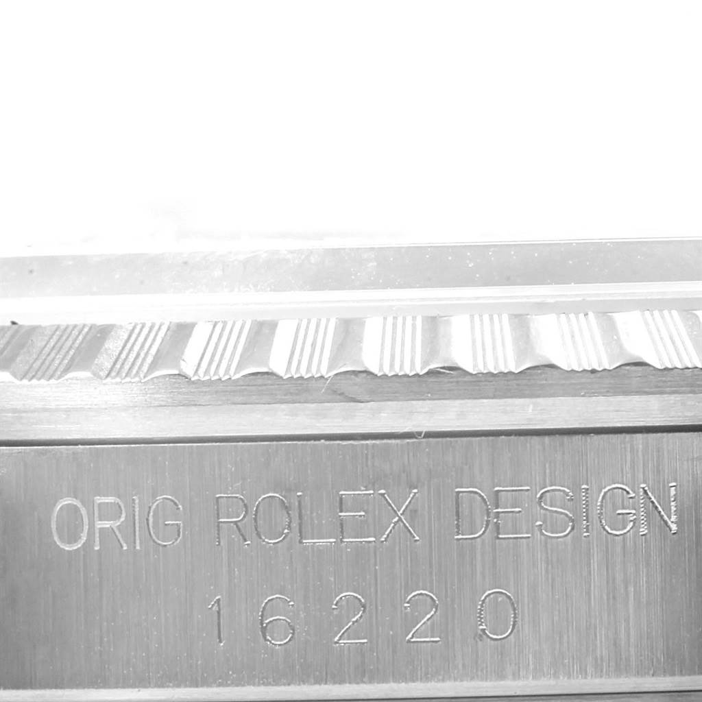 This close-up image shows the engraving "ORIG ROLEX DESIGN 16220" on the side of the bezel of a Rolex Datejust 16220 Men
s Stainless Steel Silver Dial 16220 Men
s Stainless Steel Silver Dial watch.
