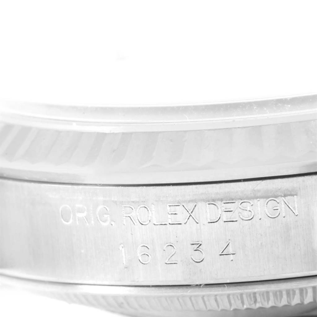 This image shows a close-up of the side view of a Rolex Datejust 16234 Men's Stainless Steel White Dial 16234 Men's Stainless Steel White Dial model, featuring engraved text and parts of the bezel and case.