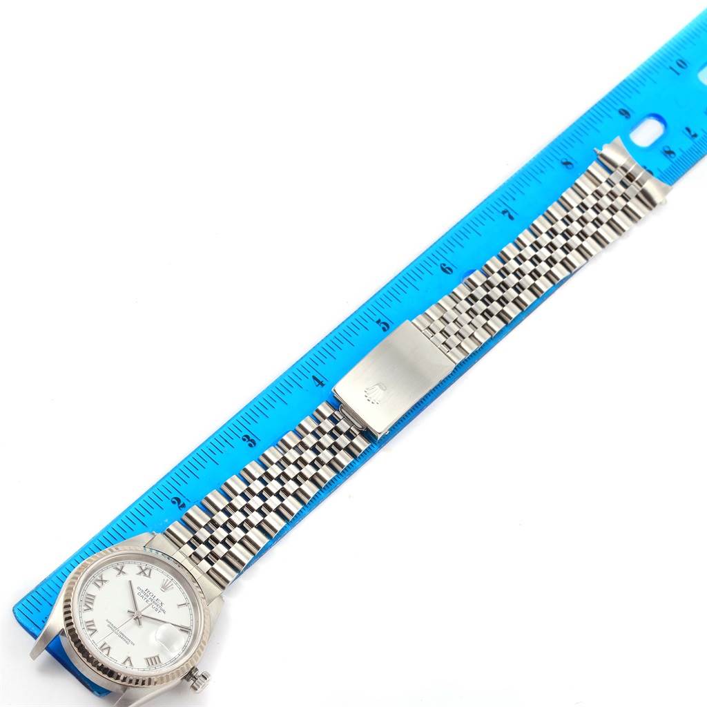 The Rolex Datejust 16234 Men's Stainless Steel White Dial 16234 Men's Stainless Steel White Dial watch is shown from a top-down angle, displaying the face, bezel, and full bracelet next to a blue ruler.