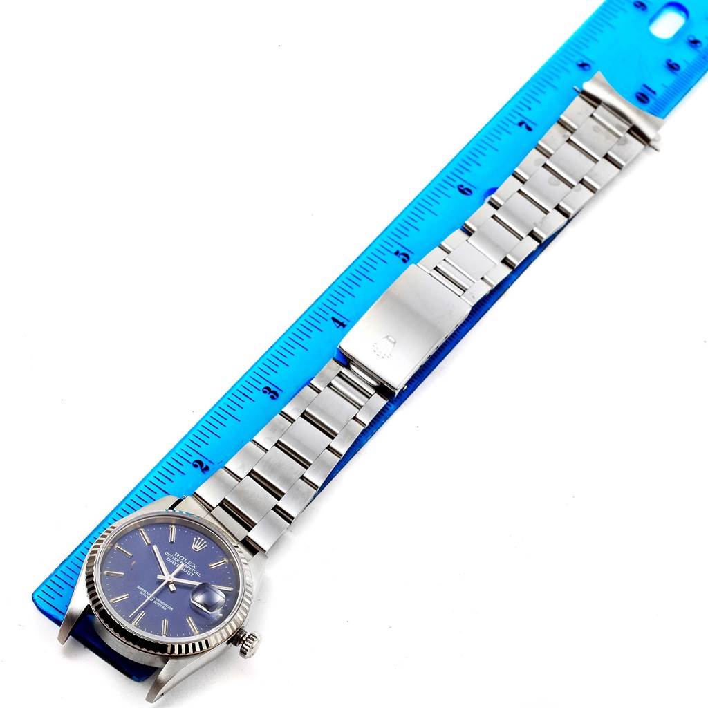 This image shows a Rolex Datejust 16234 Men's Stainless Steel Blue Dial 16234 Men's Stainless Steel Blue Dial watch laid flat next to a ruler, displaying the watch's face, bracelet, and clasp.