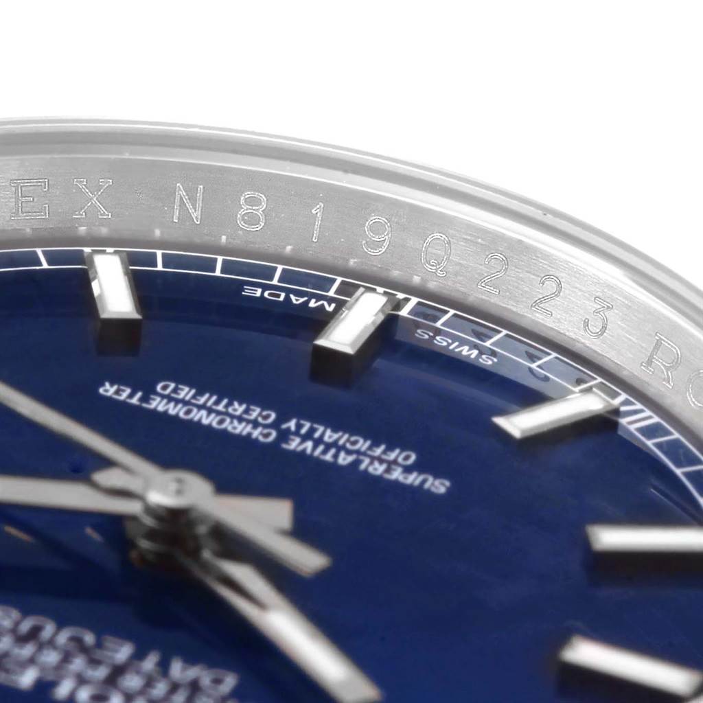 This close-up of a Rolex Datejust 116200 Men's Stainless Steel Blue Dial 116200 Men's Stainless Steel Blue Dial watch shows part of the bezel with engravings and part of the dial with markers.